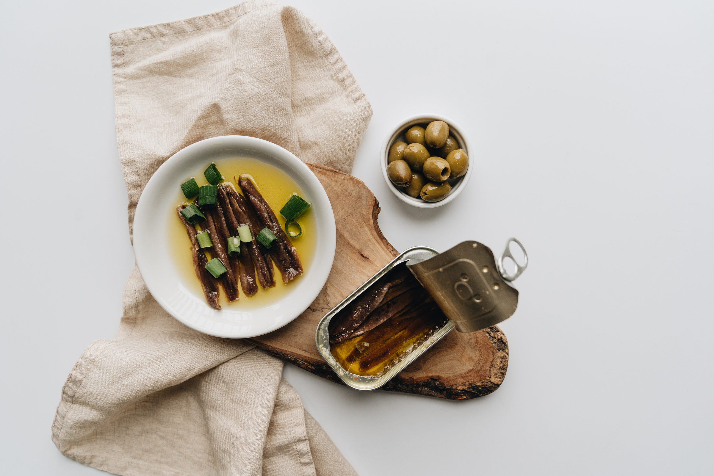 Close-Up Shot of a Can of Anchovies beside Olives